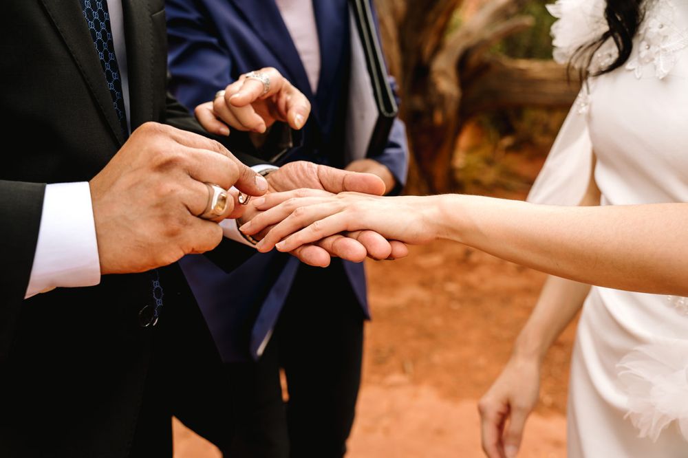 Close-up of hands exchanging rings during an outdoor Sedona wedding ceremony.