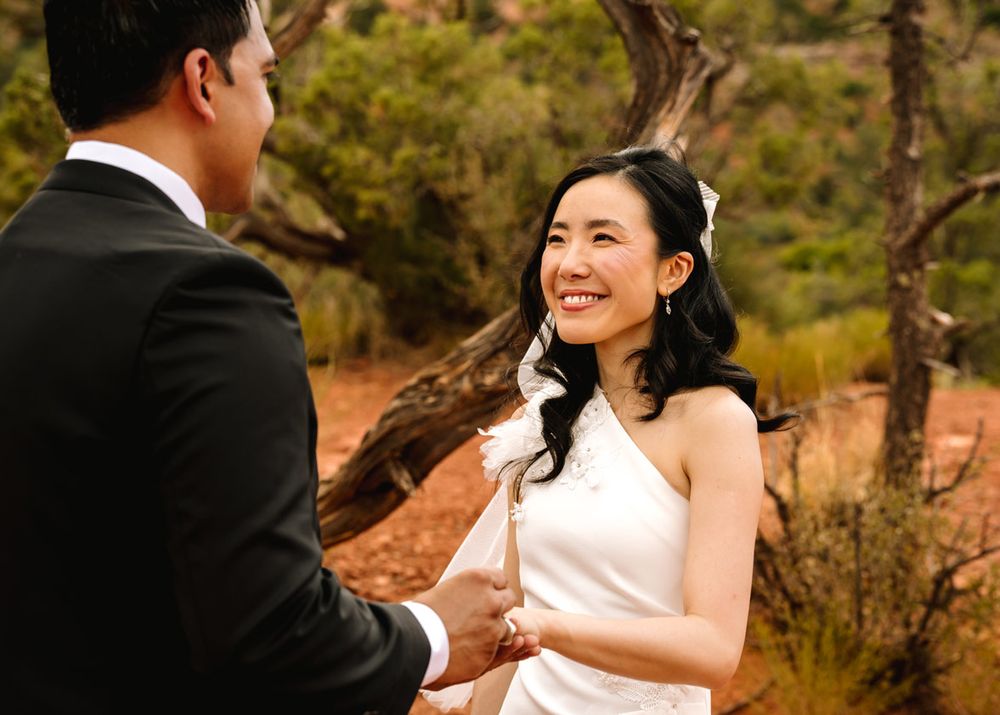 A couple shares joyful laughter during their wedding ceremony in a Sedona desert setting.