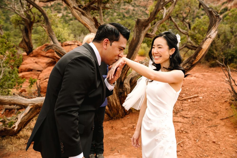A couple shares a romantic moment onSedona  red desert rocks during their wedding photoshoot.