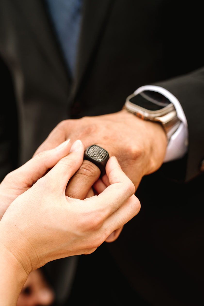 Close-up of hands exchanging a ring during a wedding ceremony.