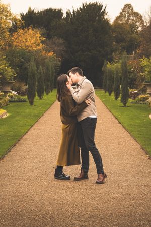 Couple shares romantic moments on gravel garden path.