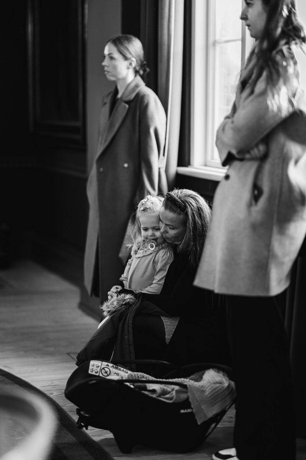 A small child sits with attendees during an indoor wedding ceremony.