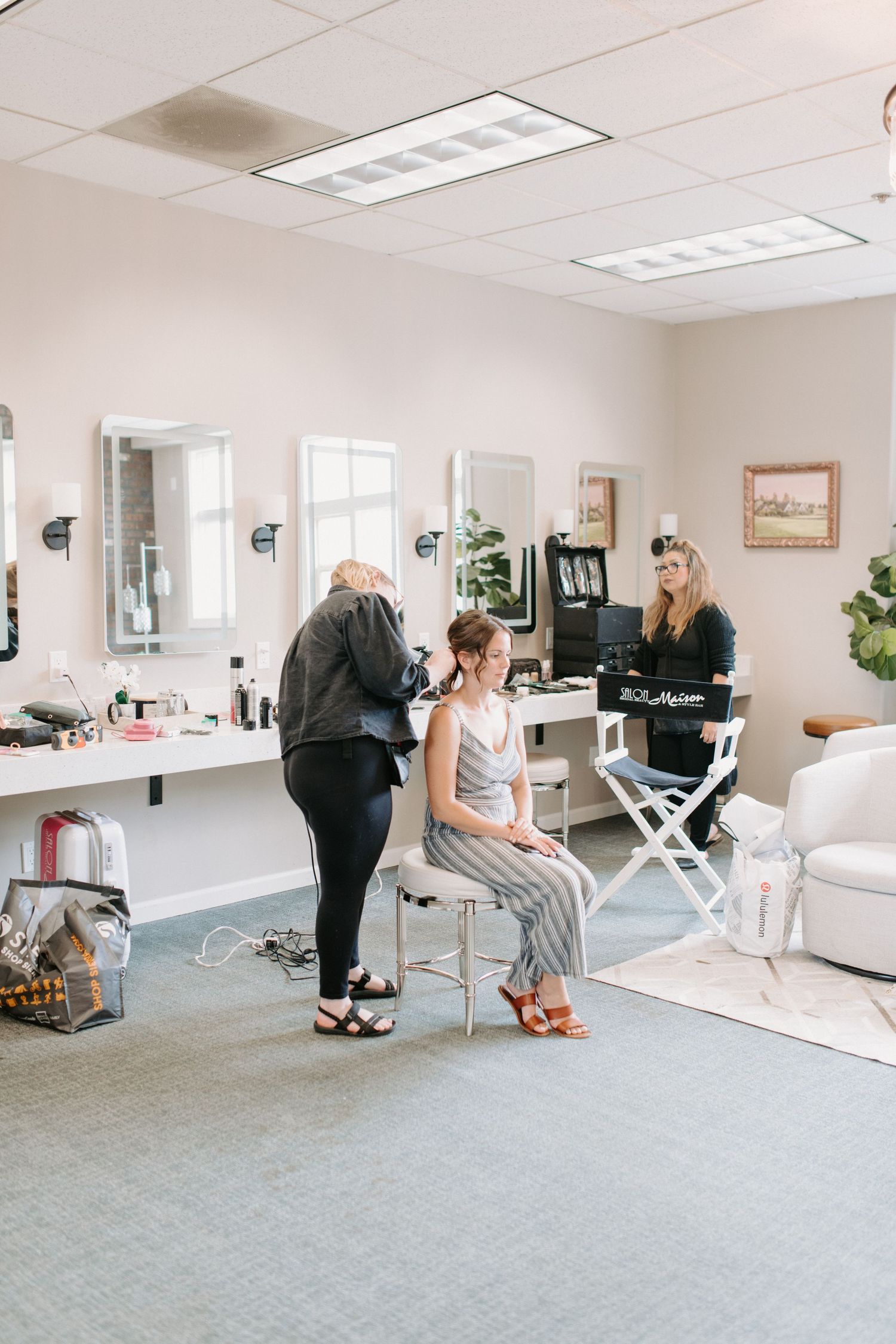 Bright indoor preparation room with mirrors, chairs and professional lighting setup.