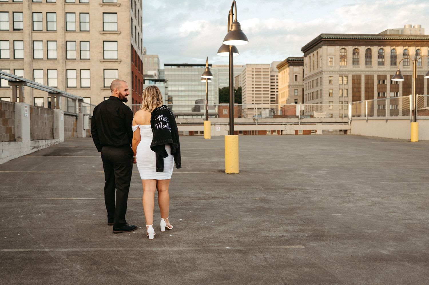 Urban rooftop setting with historic brick buildings and city architecture in background.