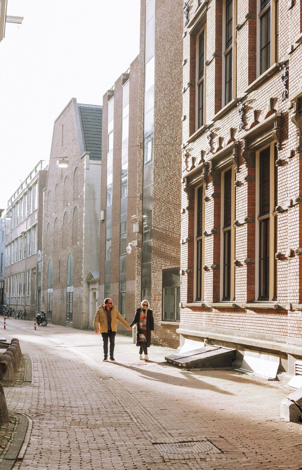 A narrow cobblestone street lined with traditional brick buildings in an old European city.