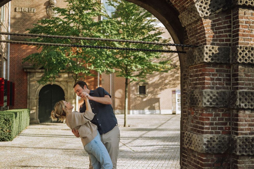 Romantic scene under brick archway with sunlight streaming through ornate architectural details.