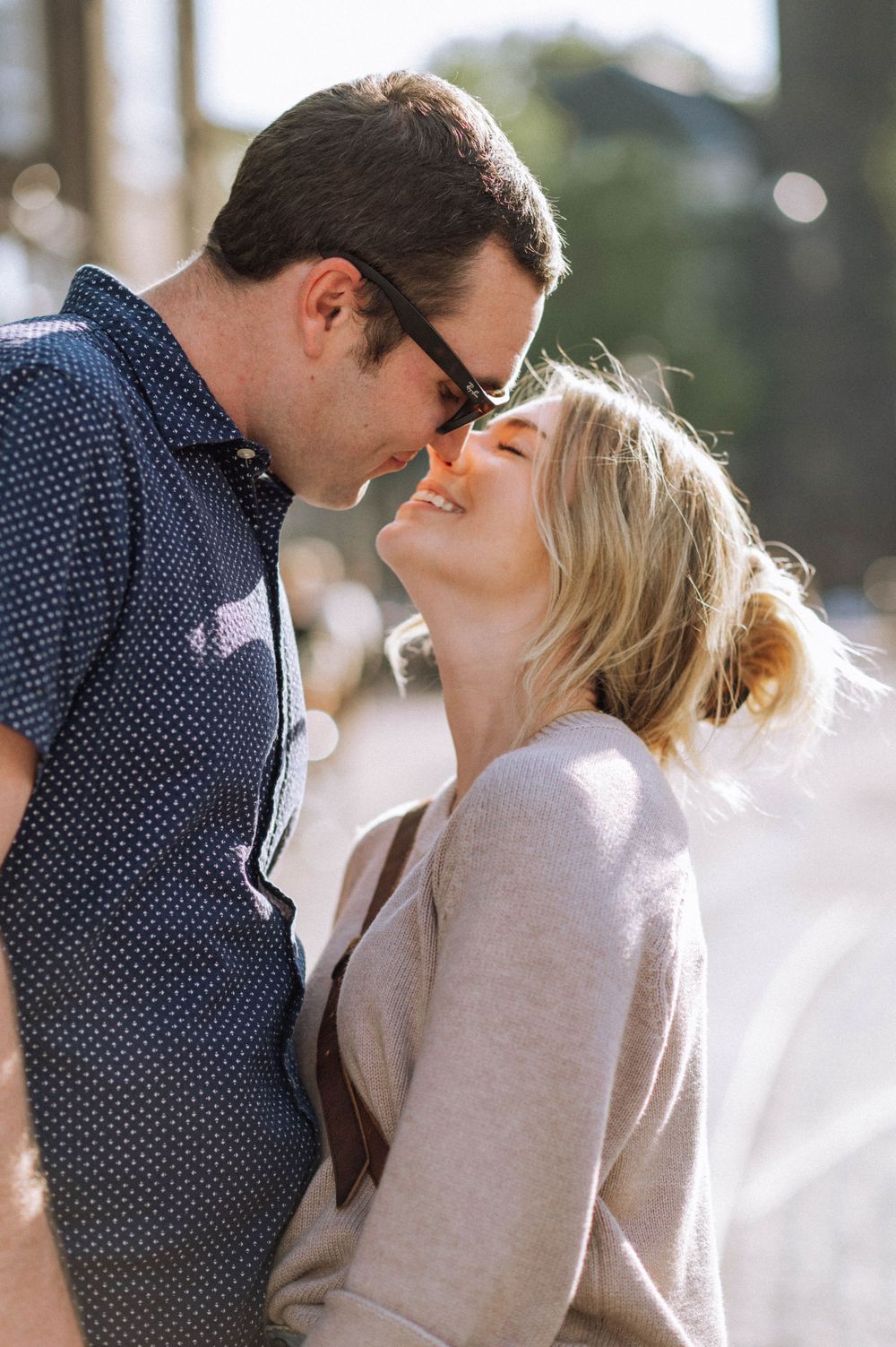 An intimate moment between a couple during a sunny outdoor photoshoot.