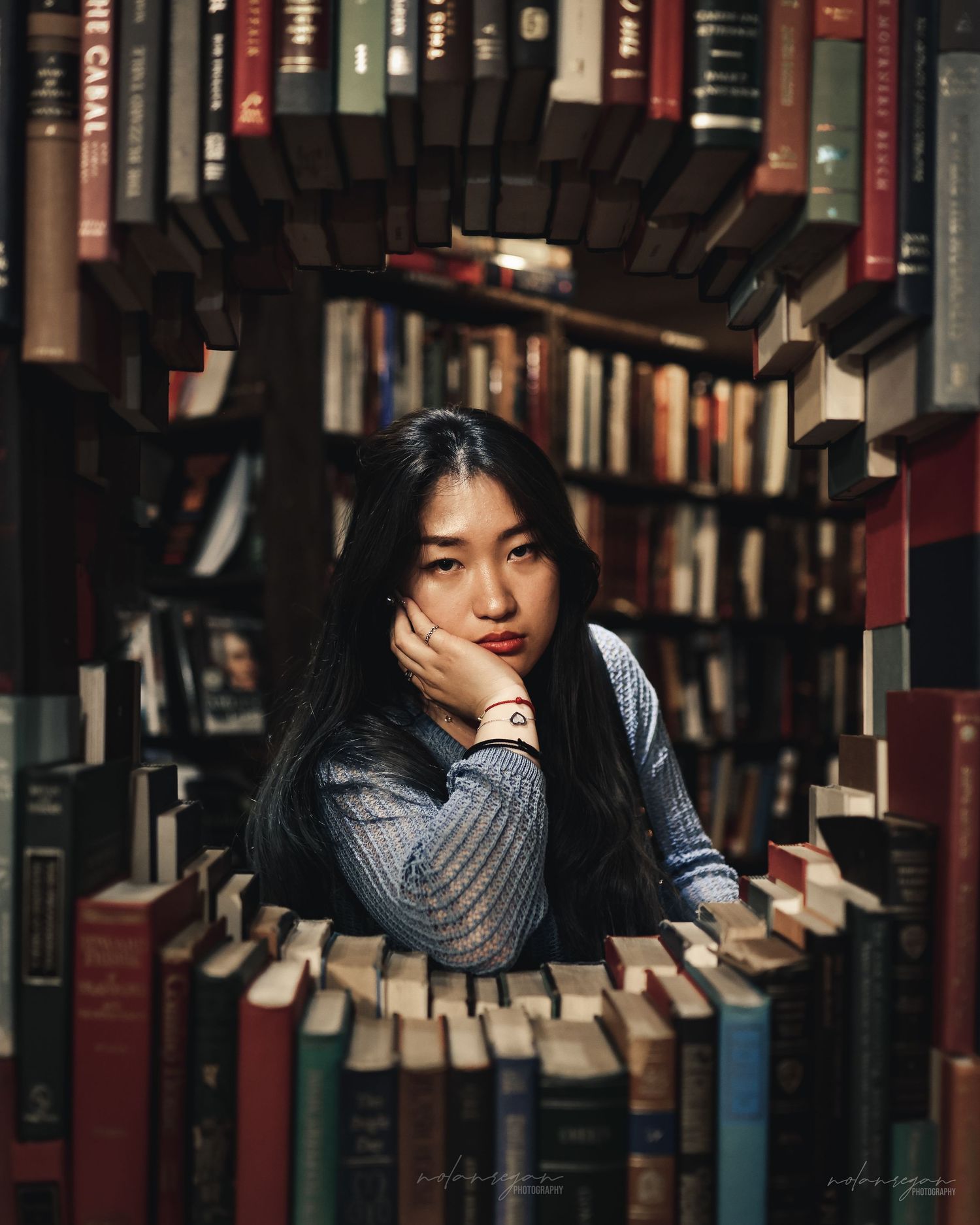 A creative portrait showing someone surrounded by books arranged in concentric circles in a library.