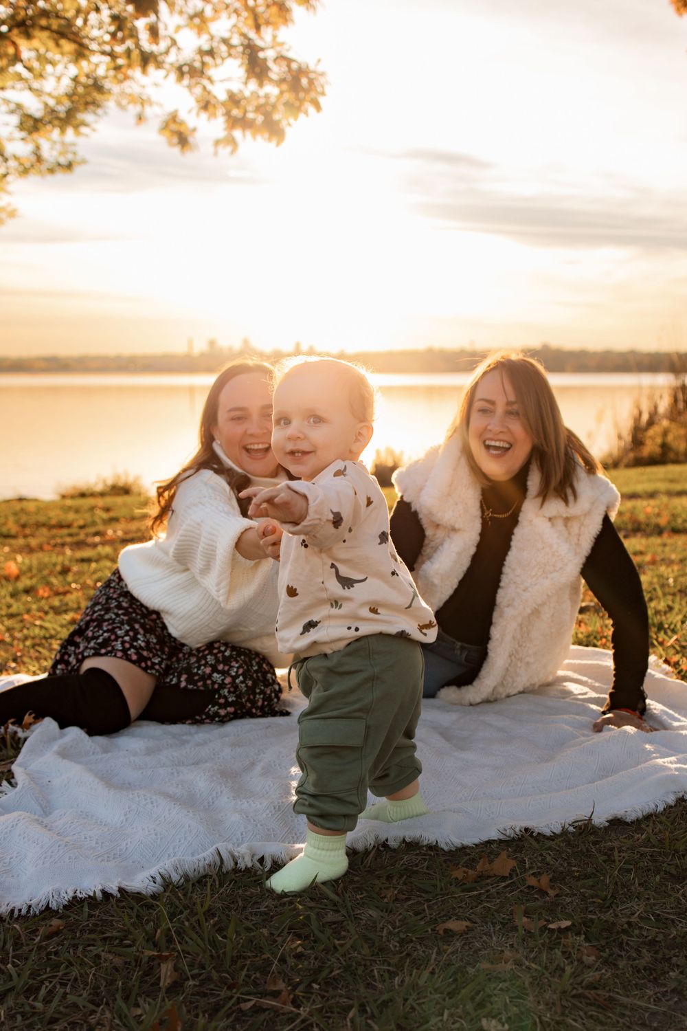 Happy gathering on picnic blanket during golden hour by the lake.