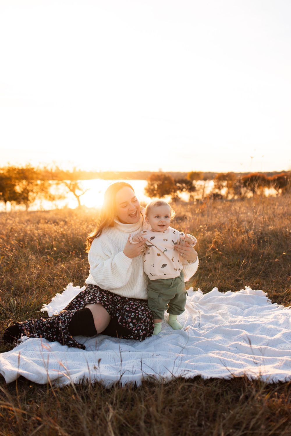 Intimate outdoor portrait during golden hour with white blanket in field.