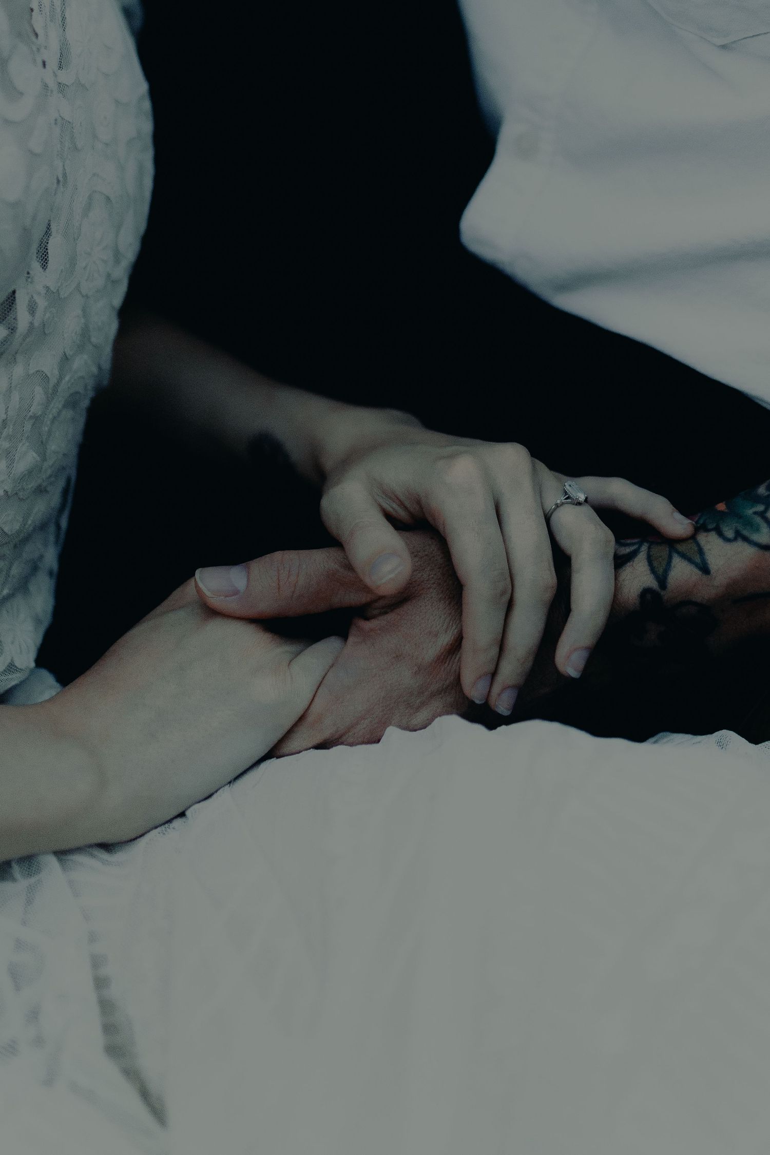 Close-up of hands gently touching and intertwining against a light background.
