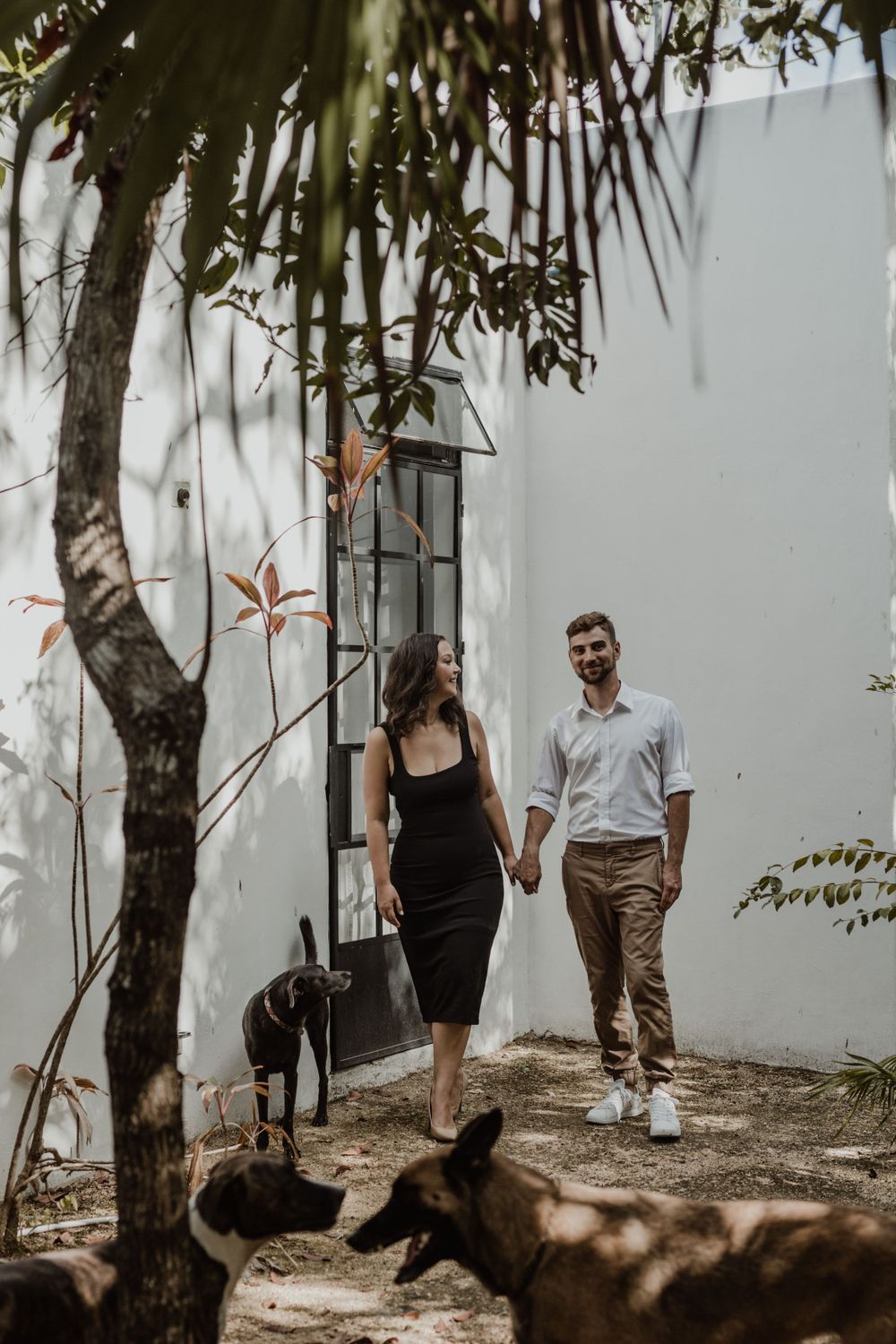 Couple walking hand in hand along garden path with tropical landscaping.