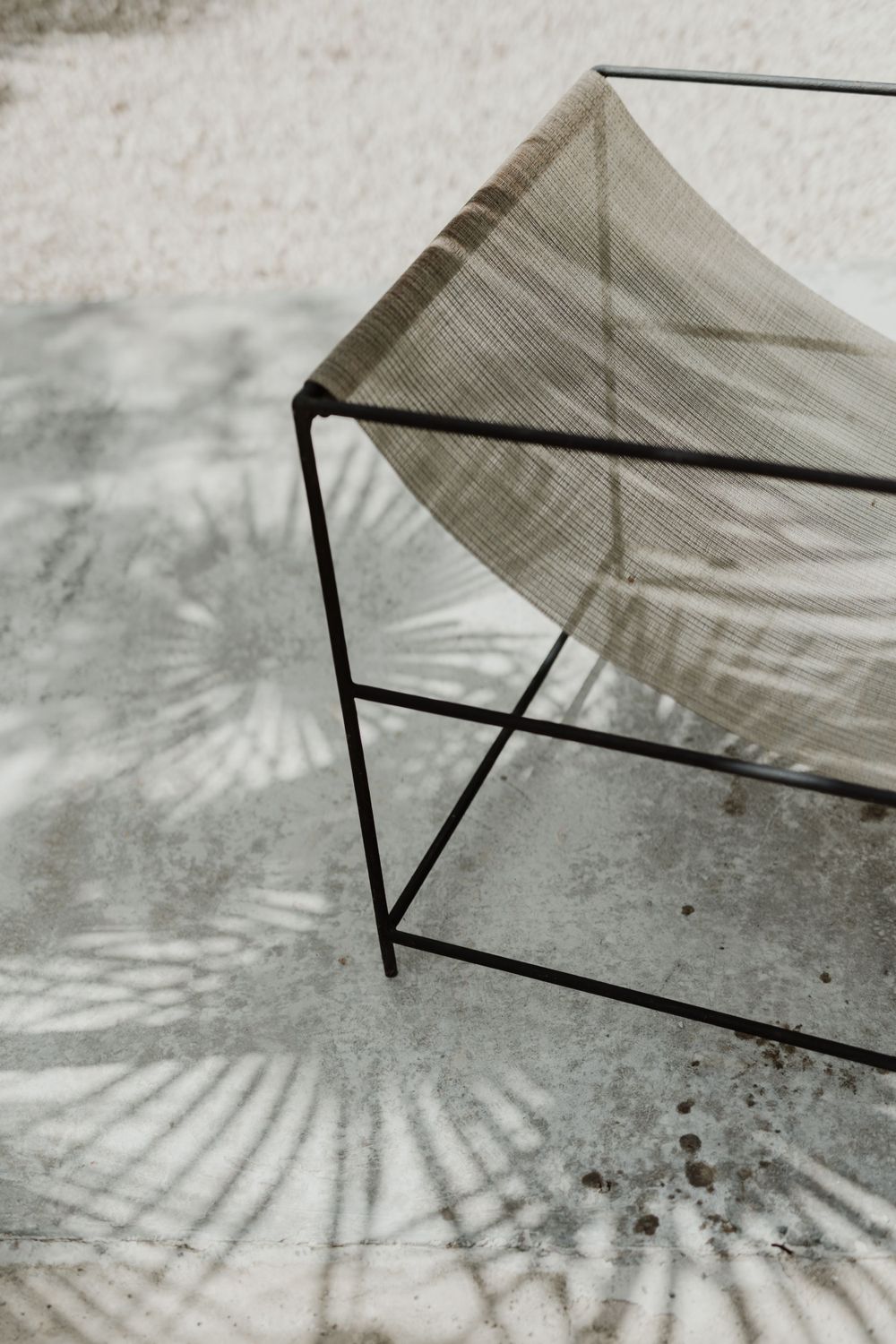 Modern geometric canopy structure casting palm frond shadows on ground.