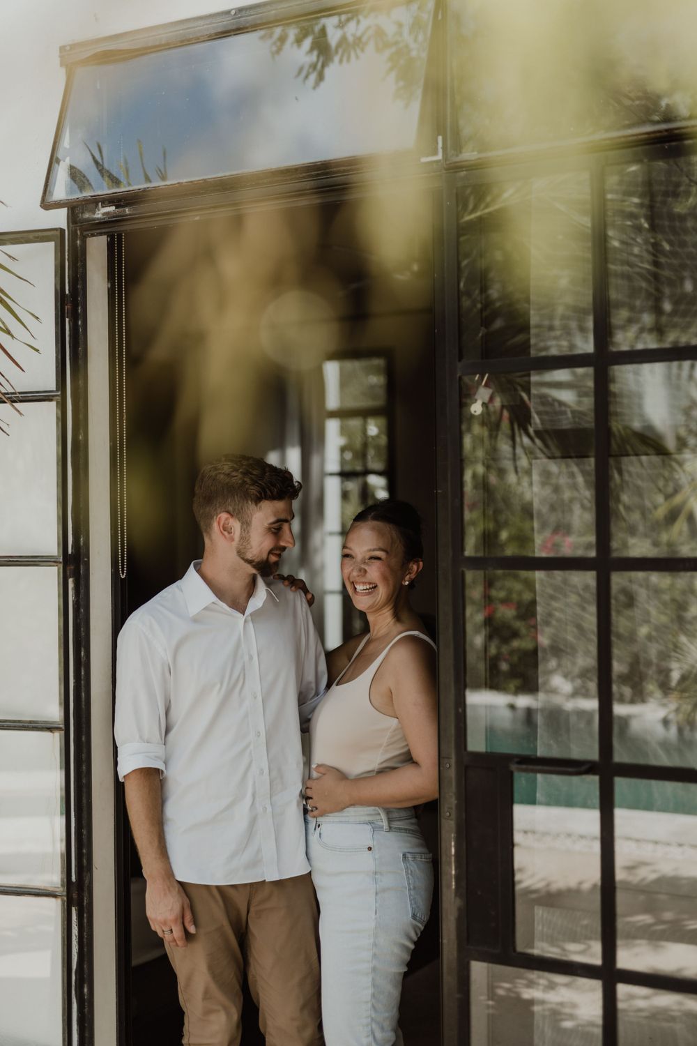 A couple shares a loving moment in a doorway with natural light streaming in.