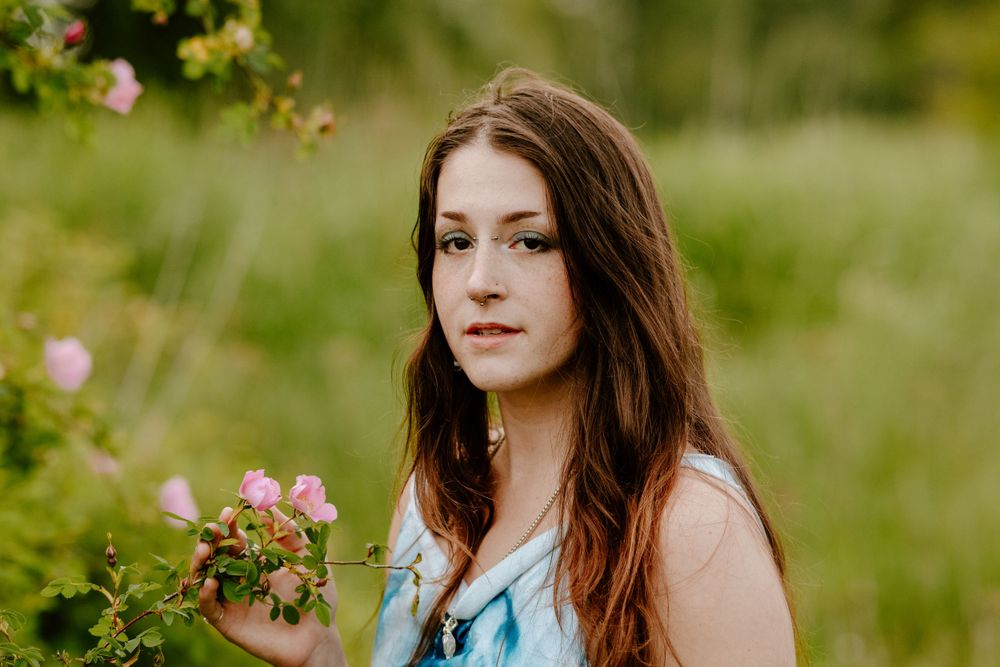 Outdoor portrait photography features a blue tie-dye dress against a natural green field background.