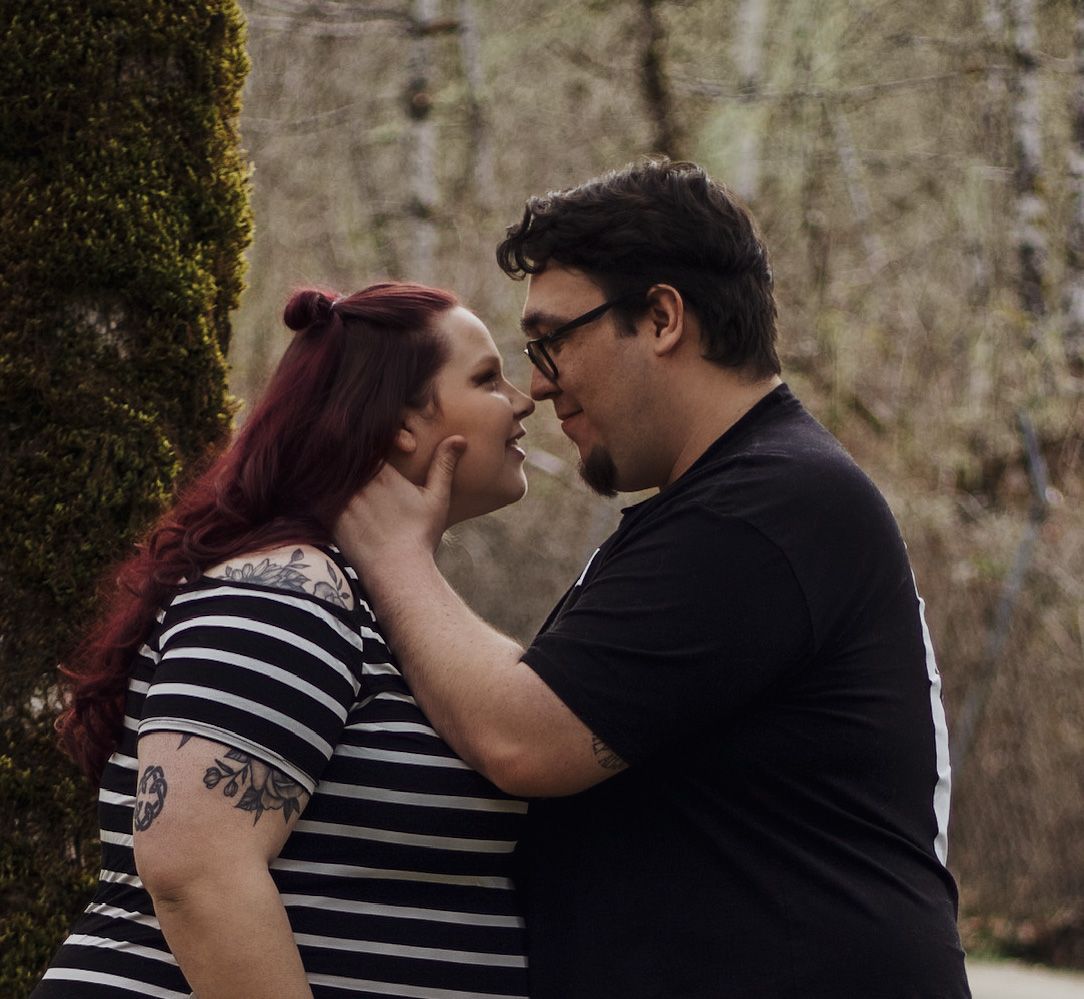 Couple sharing a romantic almost-kiss during outdoor maternity photo session.