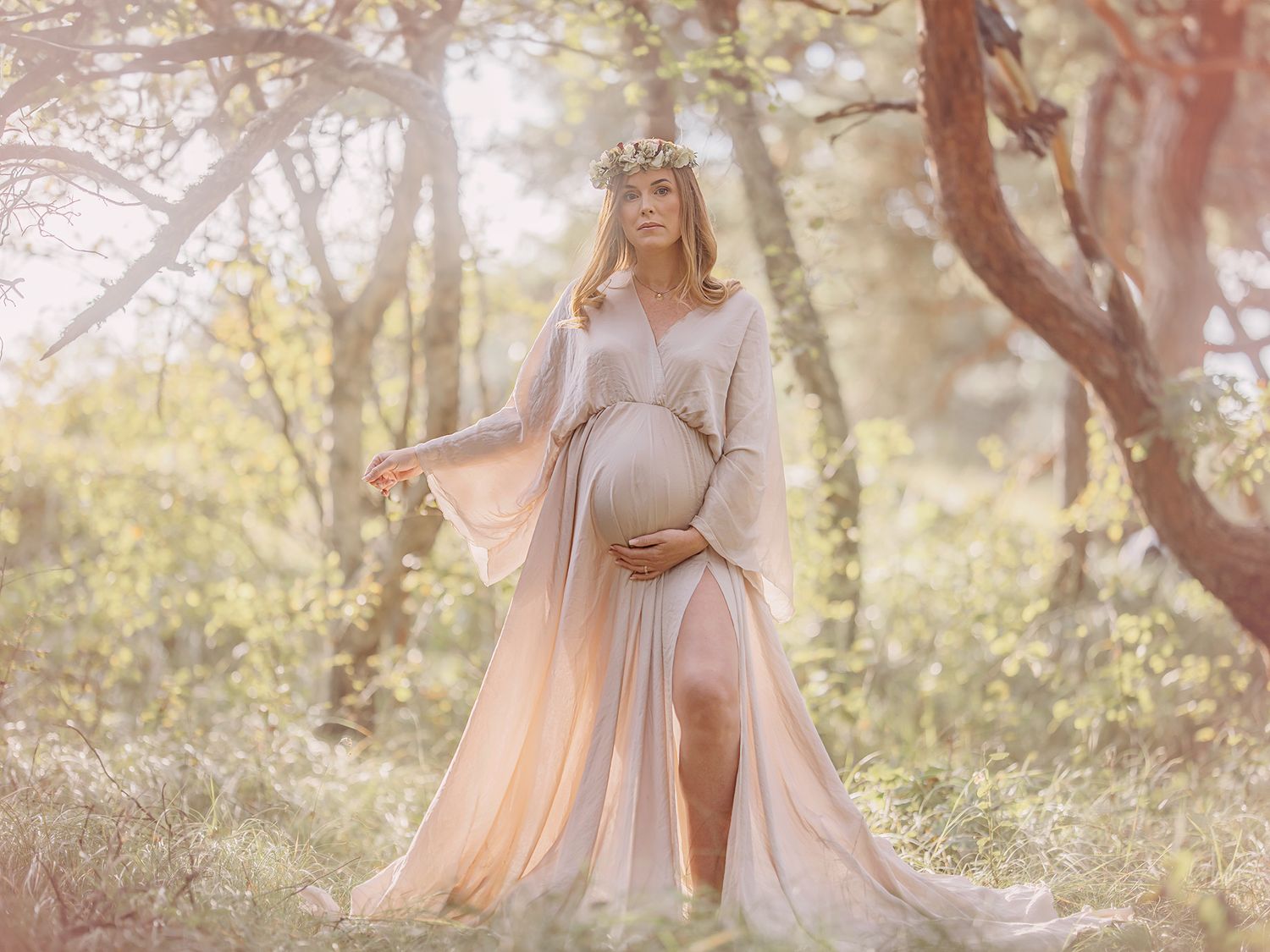 Gravid mamma står i motljus i skogen, gravidfotografering i västerås, pastell, MemoriesbyM.se
