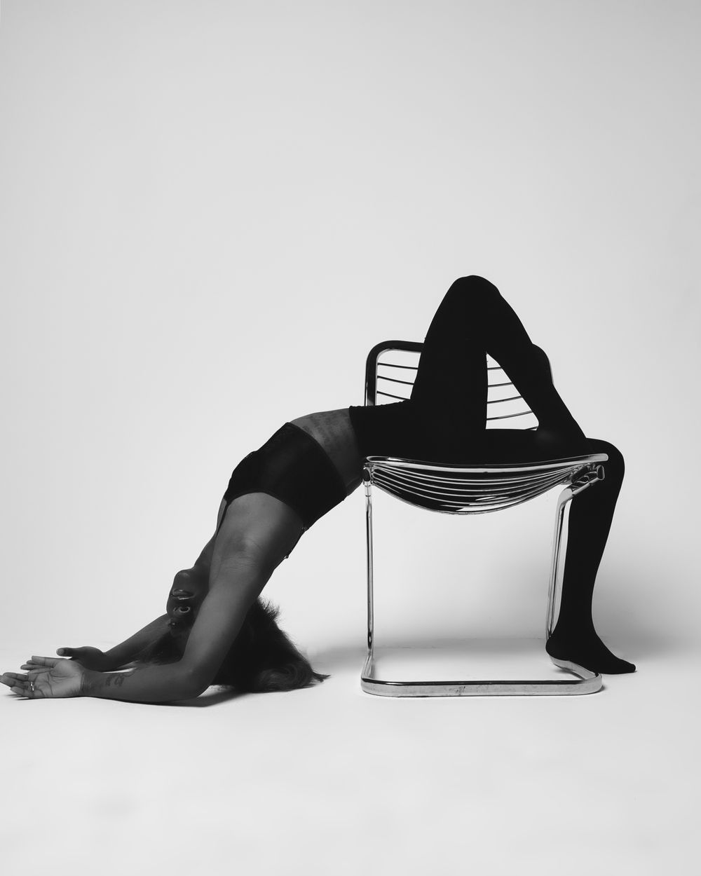Contemporary black and white photo showing flexible dance pose on modern chair.