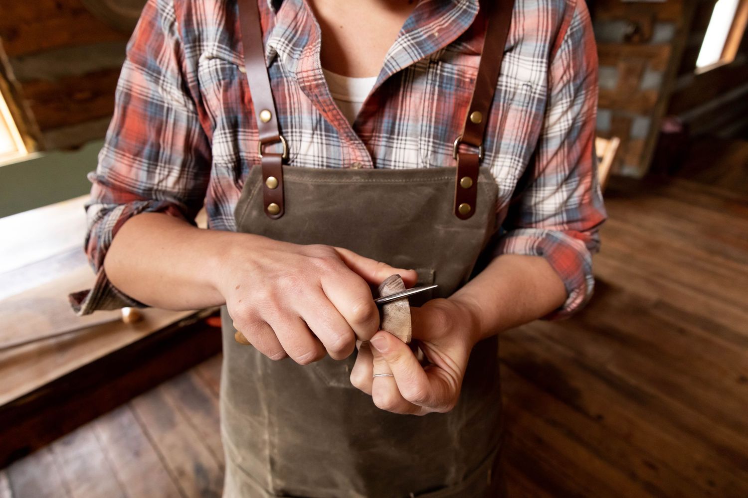 Photo of a woman woodworker hand carving a spoon  and wearing an apron during a product photography shoot for Lineage Goods,  Virginia