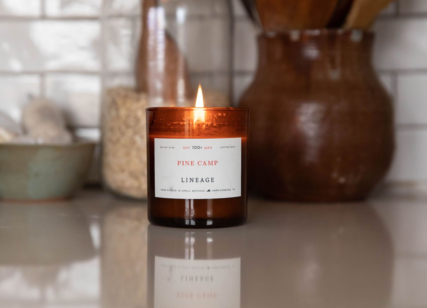 Photo of a Lineage brand candle on a countertop with white subway tile in a kitchen