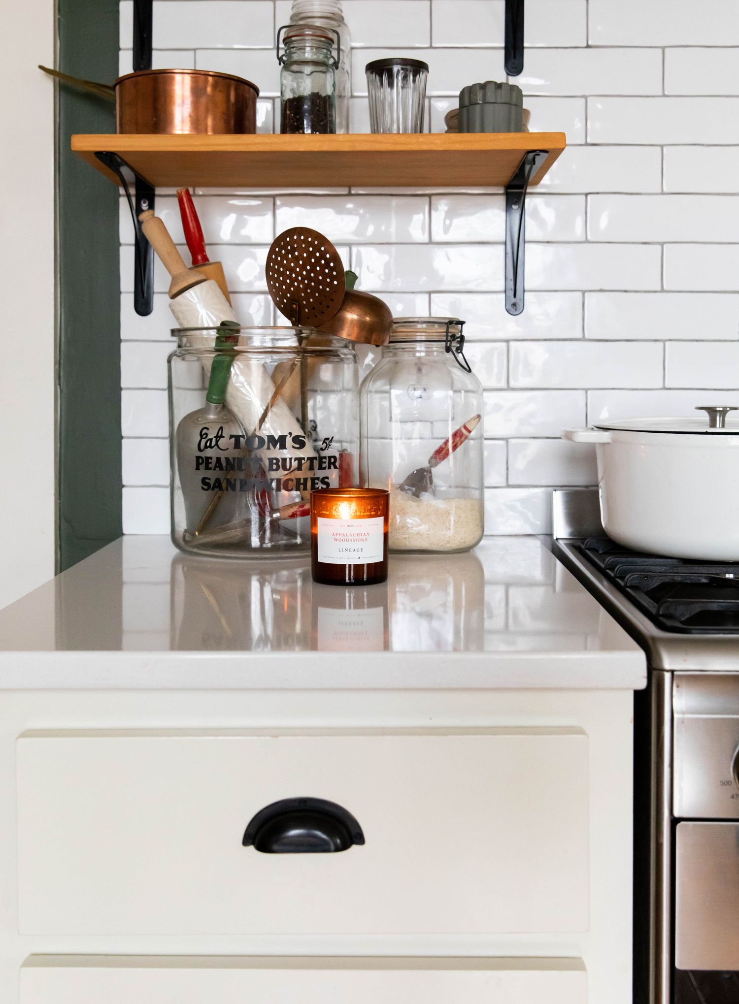 Photo of open shelving and white subway tile in a kitchen with dark green walls