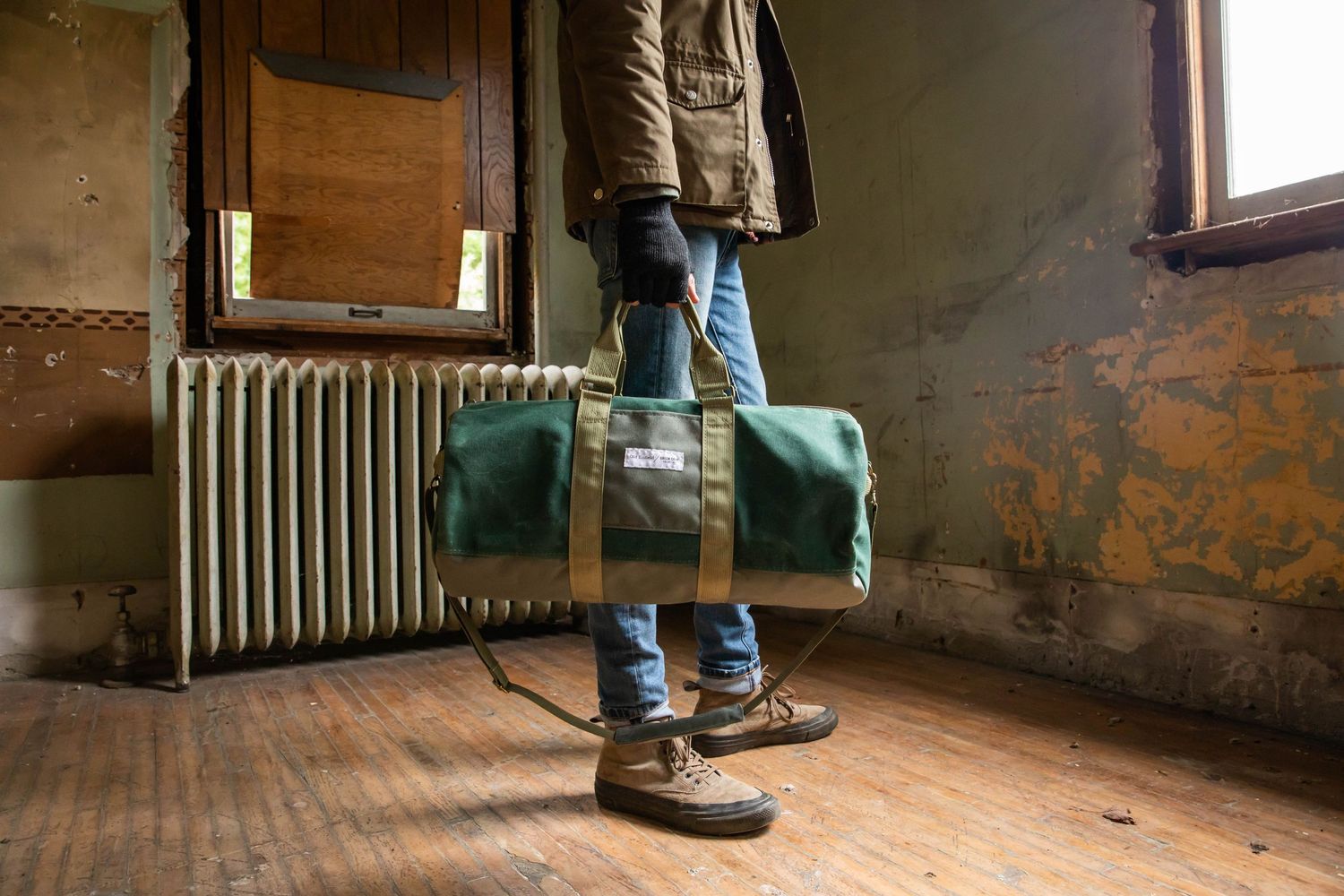 Photo of a man holding a duffel bag in old building, for a product photography photo shoot for Green Cove Collective