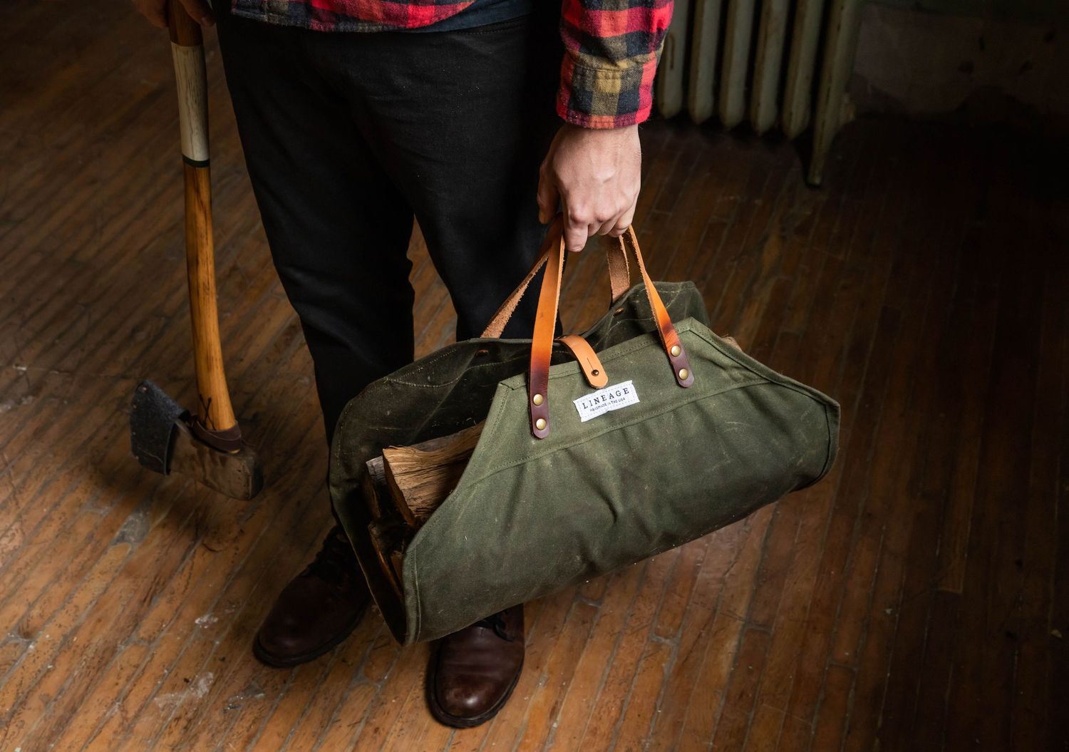Photo of a man holding an ax and a wood carrier, wearing a flannel shirt, during a product photography shoot for Green Cove Collection