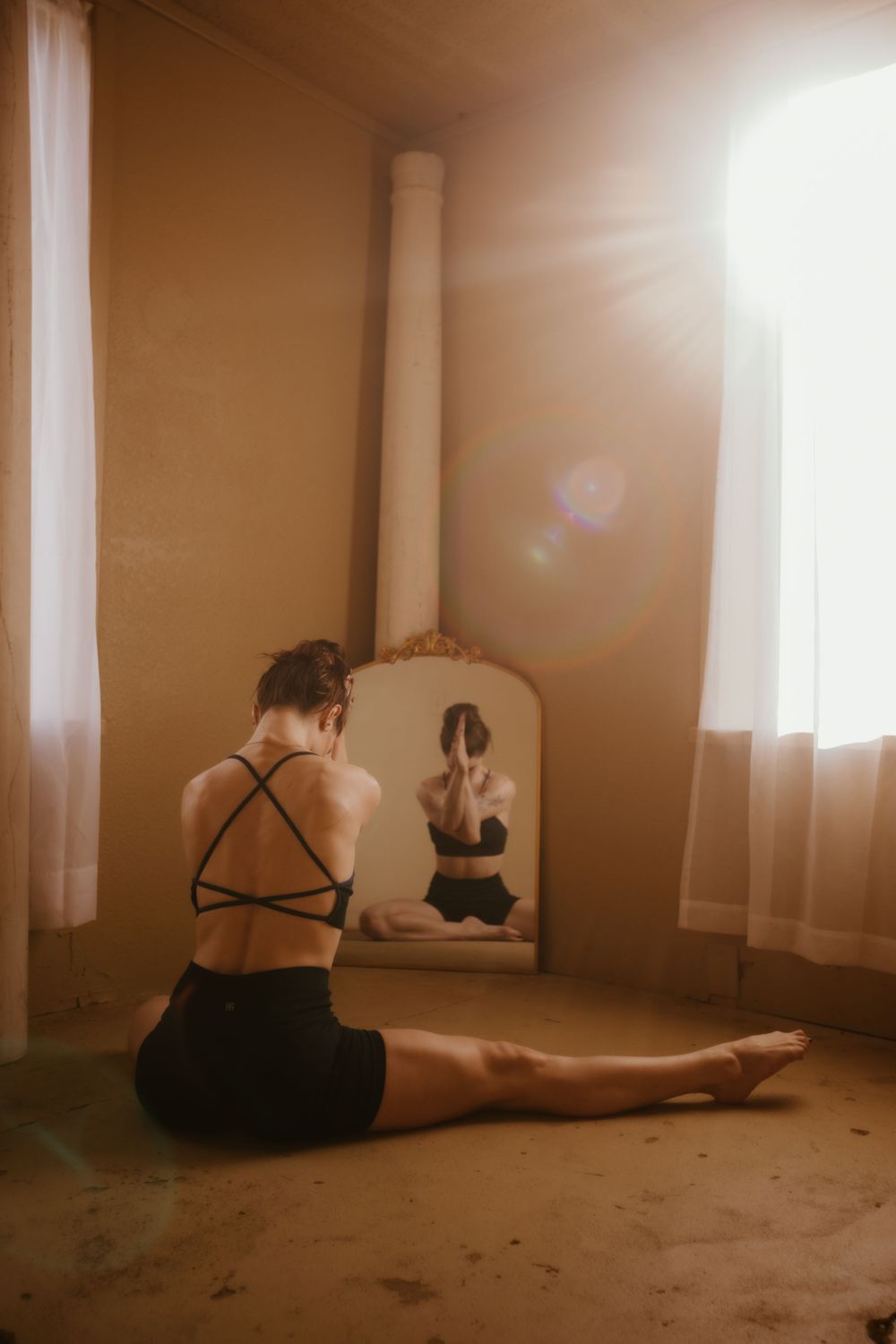 A series of sepia-toned photos showing a figure in black sitting on a floor in an empty sunlit room.