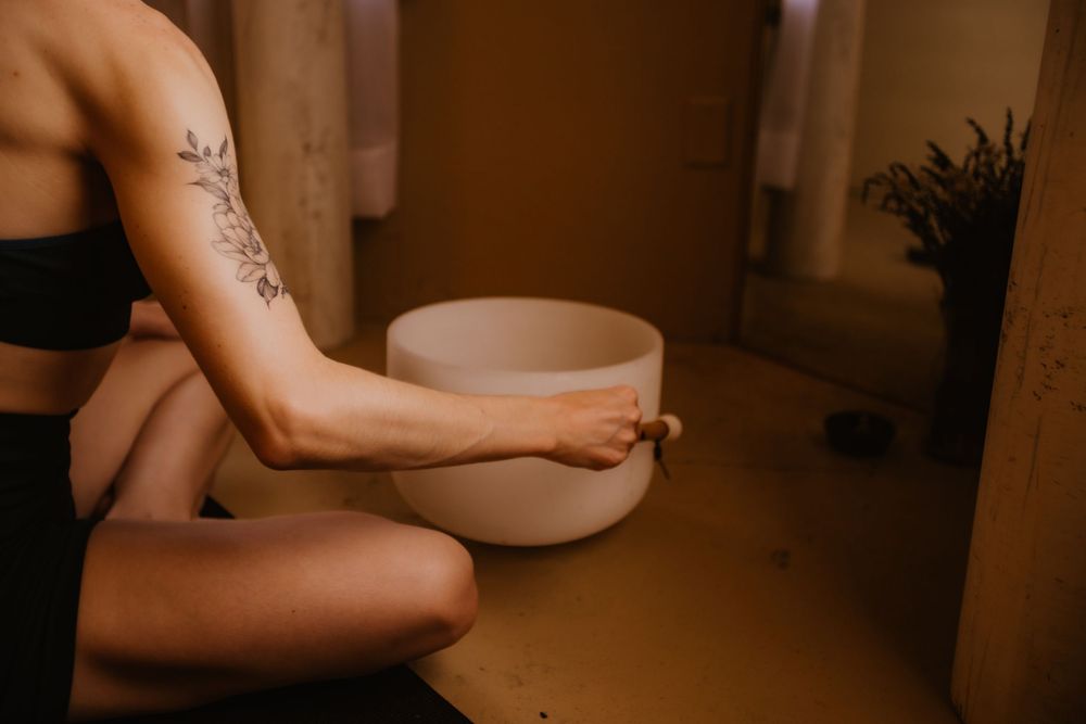 Person soaking their feet in a white ceramic bowl filled with water in a dimly lit room.