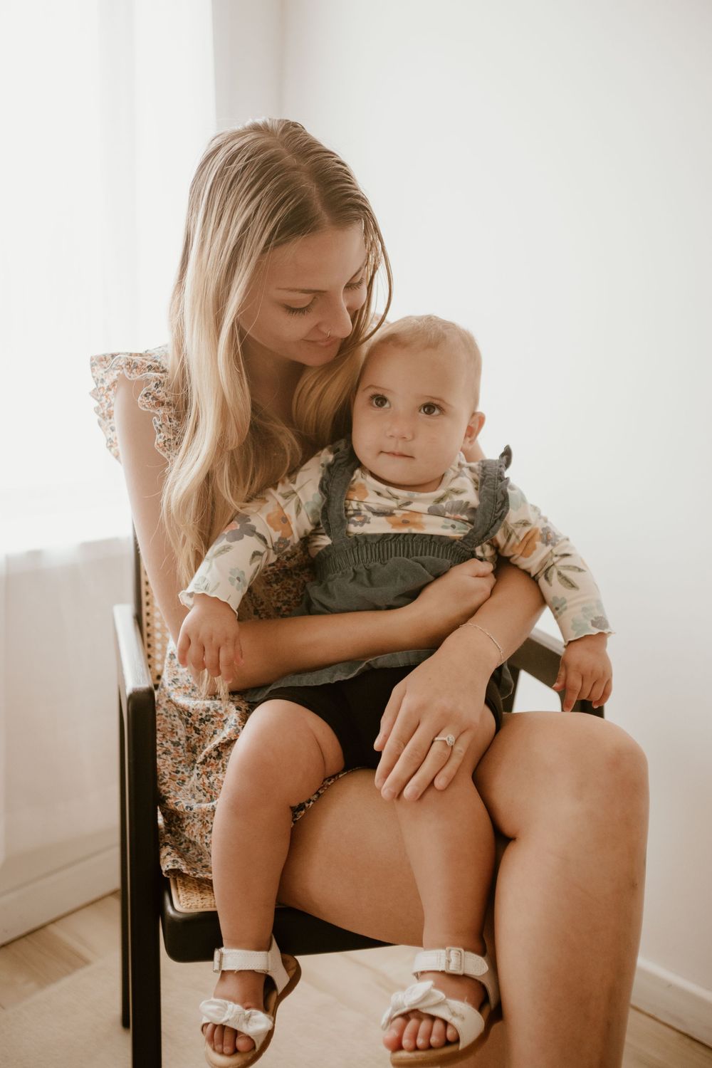 A tender moment between parent and child sitting on a chair in soft natural light.