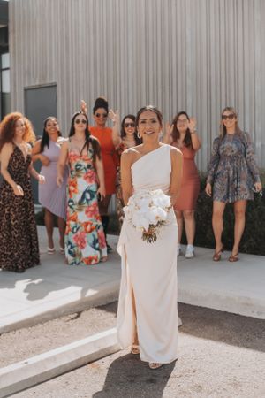 Wedding party in mix of floral and solid dresses poses behind bride in elegant white gown.