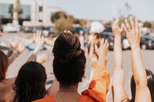A crowd of people raising their hands in celebration during an outdoor event.
