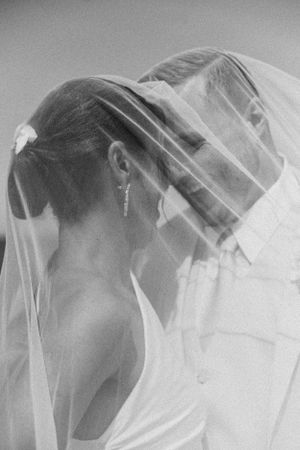 An artistic black and white portrait of a bride wearing a delicate veil.
