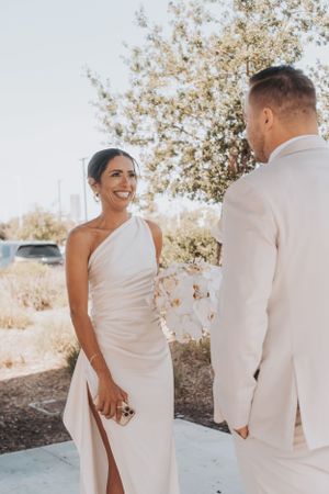 A wedding couple in elegant white attire shares a joyful moment on their special day.
