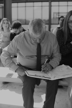 A person in business attire reviews and signs documents at an indoor gathering.