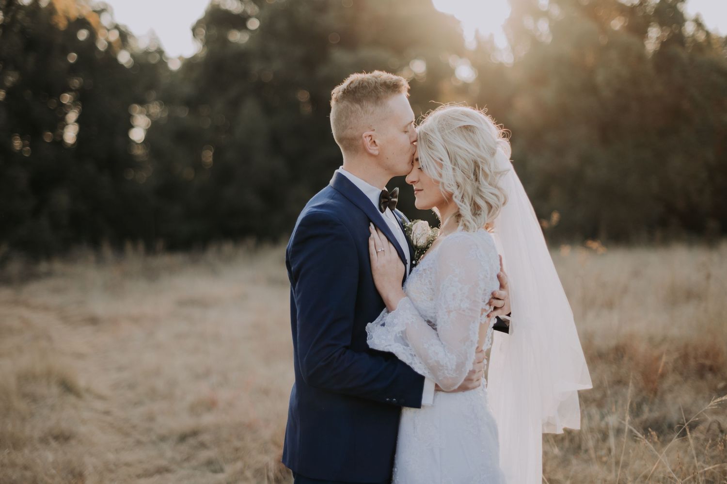 Romantic sunset portrait of newlyweds in golden afternoon light.