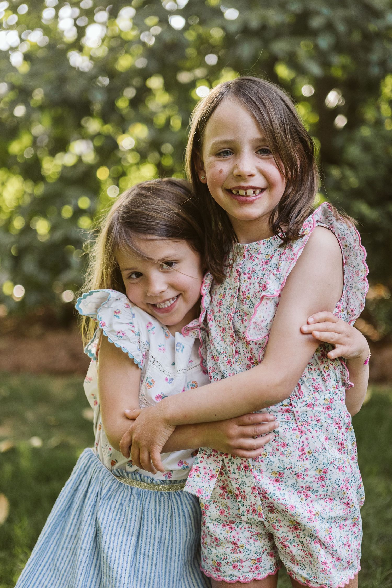 Sweet outdoor portrait of two girls hugging in matching spring outfits during a family portrait shoot