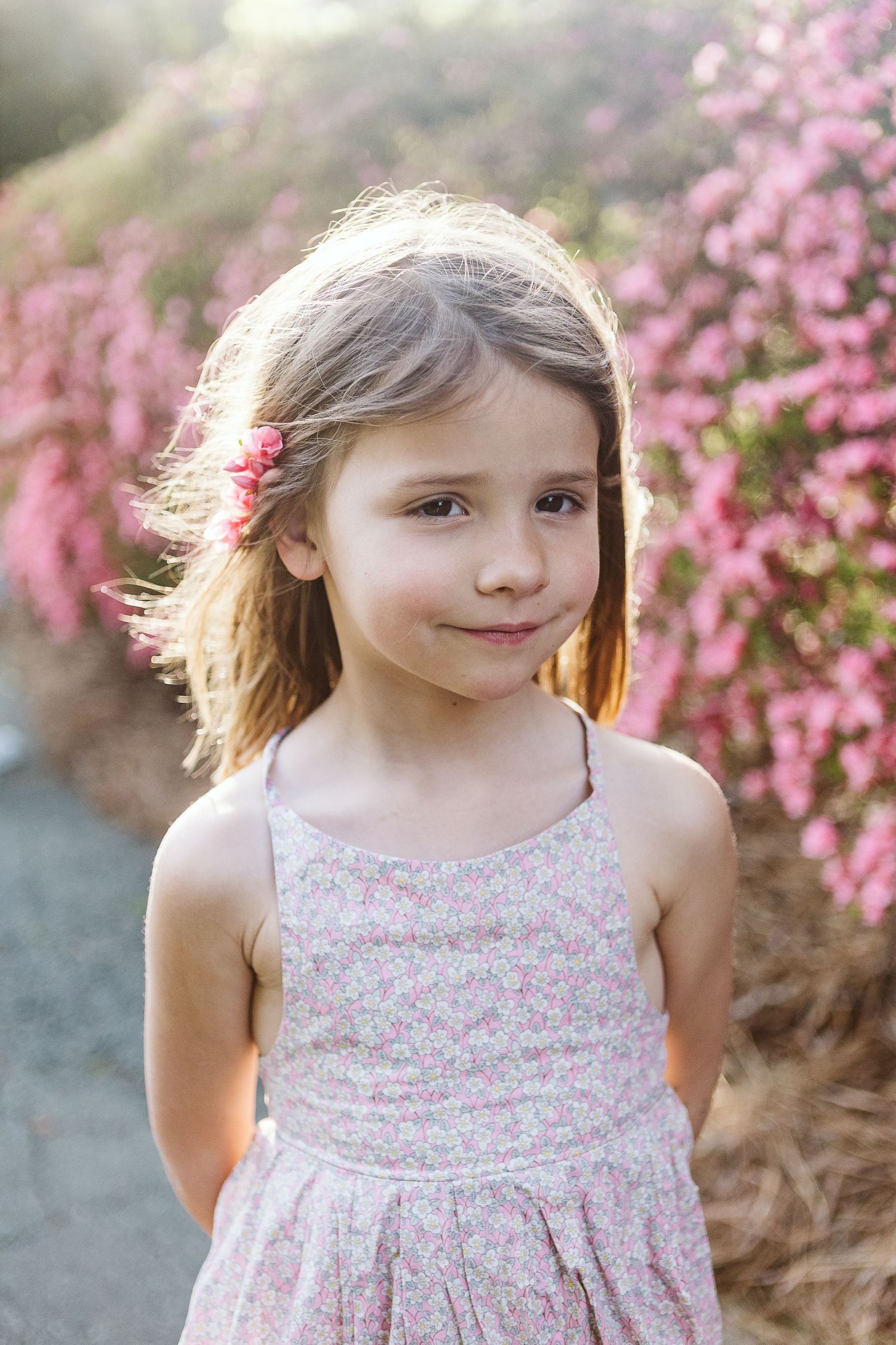 Sweet outdoor portrait of child smiling in soft sunlight, dressed for spring