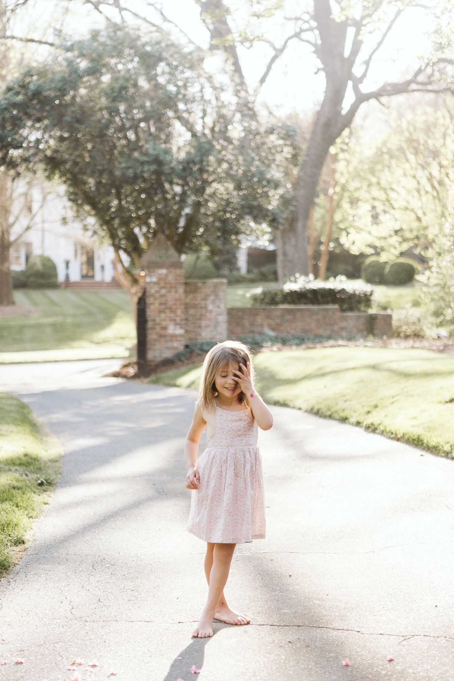 A sweet portrait of a young girl playing outside joyfully during a sunlit family photo session, dressed for spring