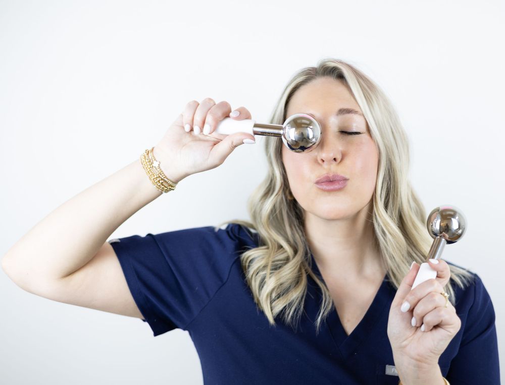 A medical professional in navy scrubs holding and comparing different stethoscopes against a white background.