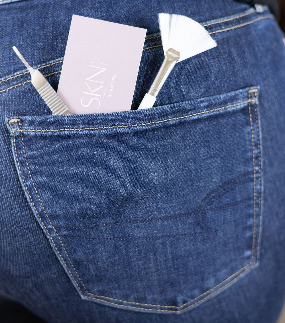 Hair combs and tools peek out from a blue denim jeans pocket, showing salon styling essentials on the go.