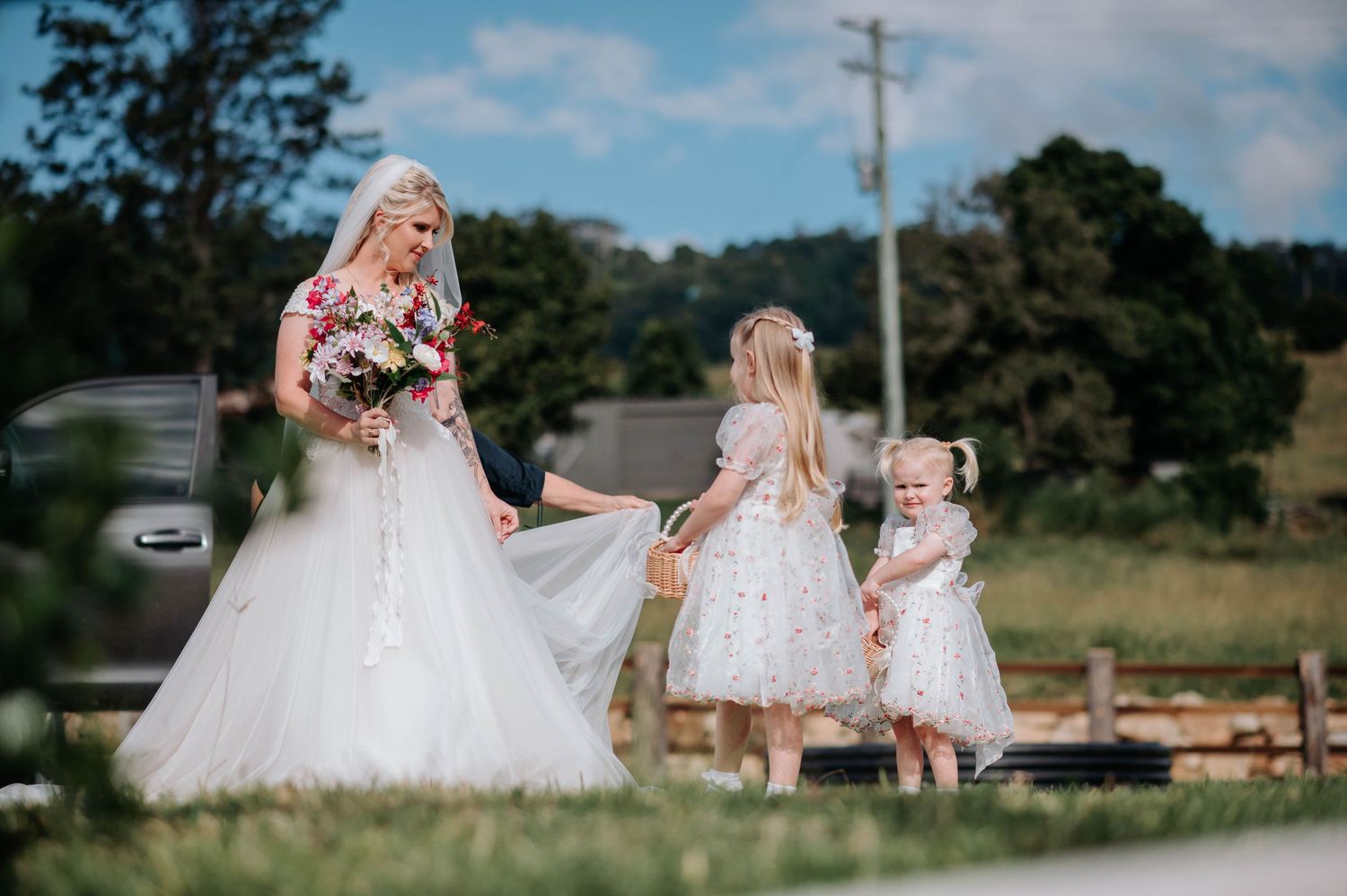 Wedding party in white dresses standing together in scenic outdoor setting.