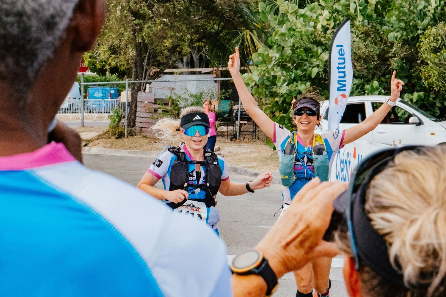 Runners celebrating and high-fiving at an outdoor trail race event in a park setting.