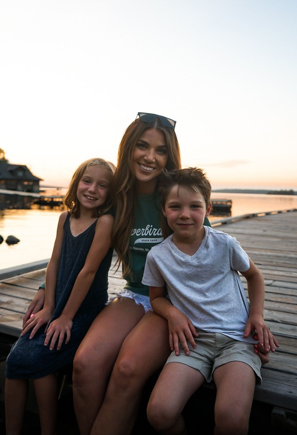 Group sitting together on a wooden dock at sunset.