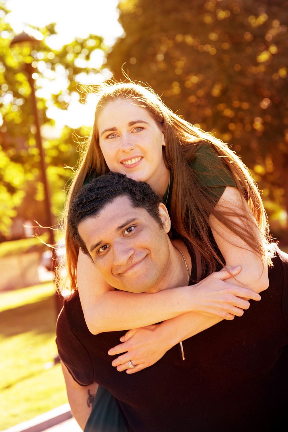 A happy couple embracing outdoors with sunlit golden foliage in the background during sunset. (University of Rochester New York)