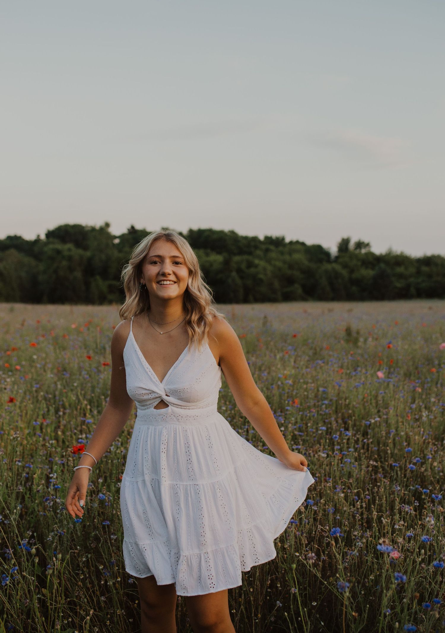 A flowing white summer dress stands out against a field of colorful wildflowers during golden hour.