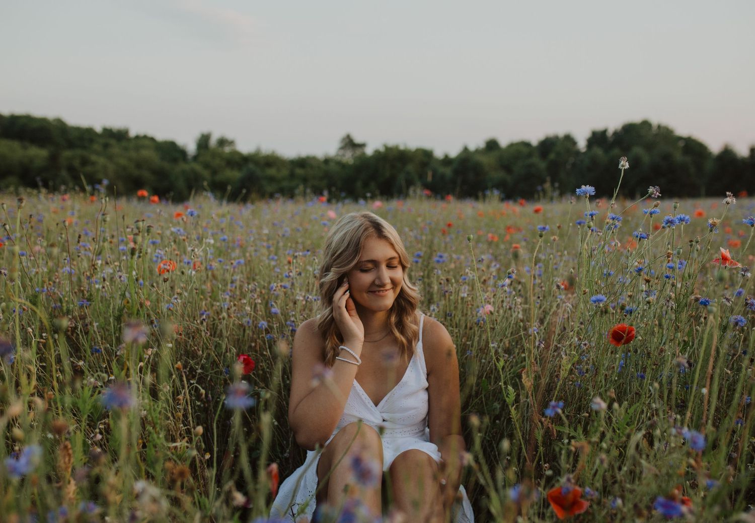 A dreamy summer portrait captured in a field of mixed wildflowers at dusk.