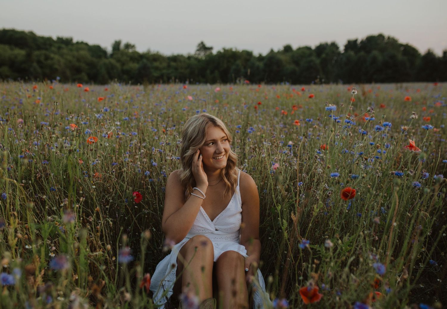 White dress contrasts beautifully against a natural backdrop of wildflowers and evening sky.