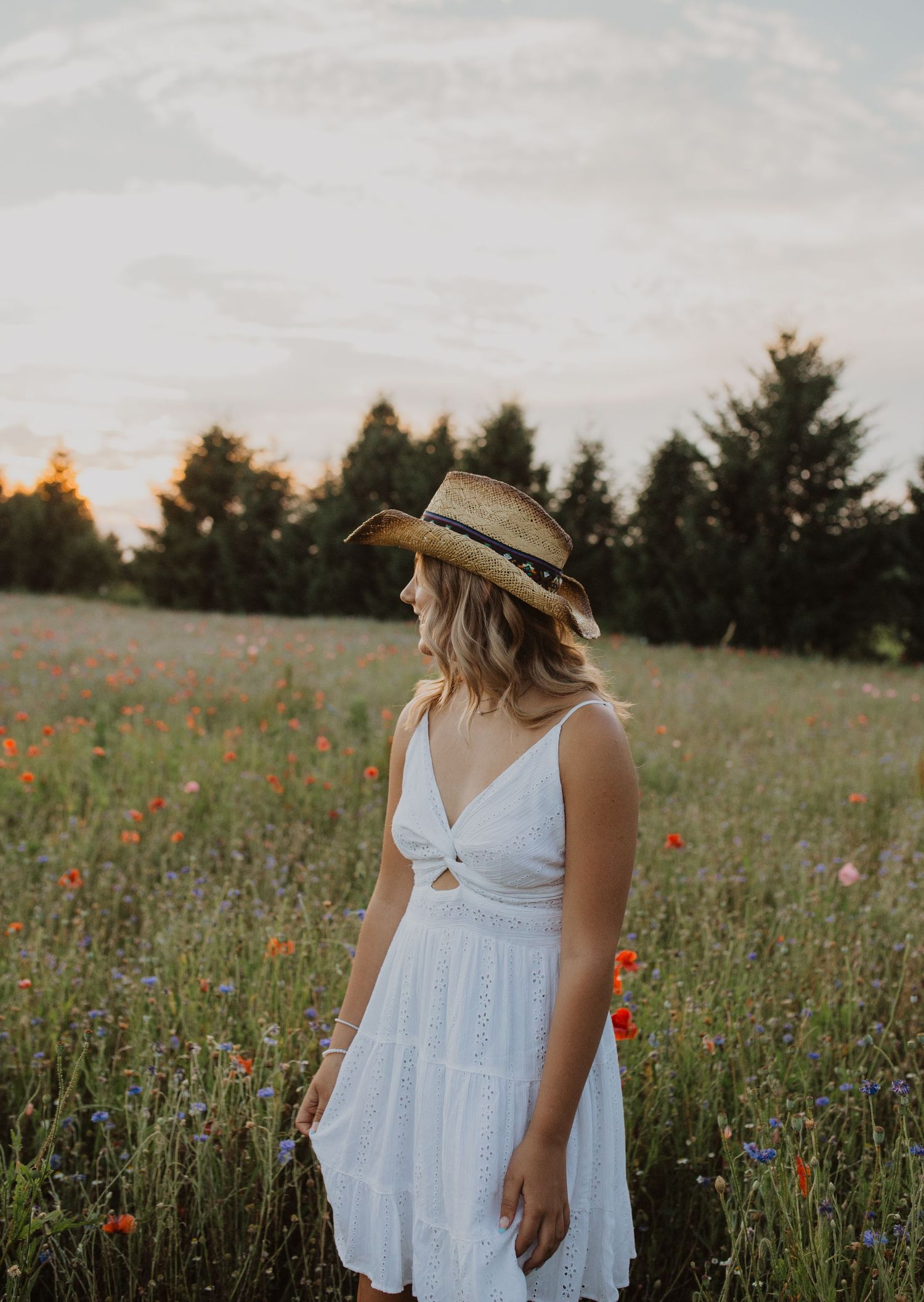 White sundress and straw hat in a wildflower meadow at sunset.