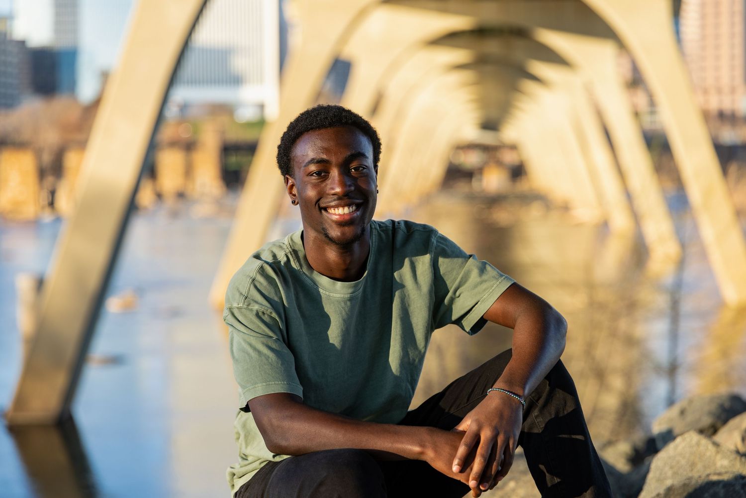 Person sitting by bridge architecture during golden hour photoshoot.